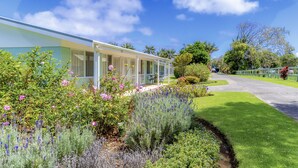 A modern house with a covered porch, surrounded by well-maintained gardens and a clear sky. - Aloha Apartments (Norfolk Island)