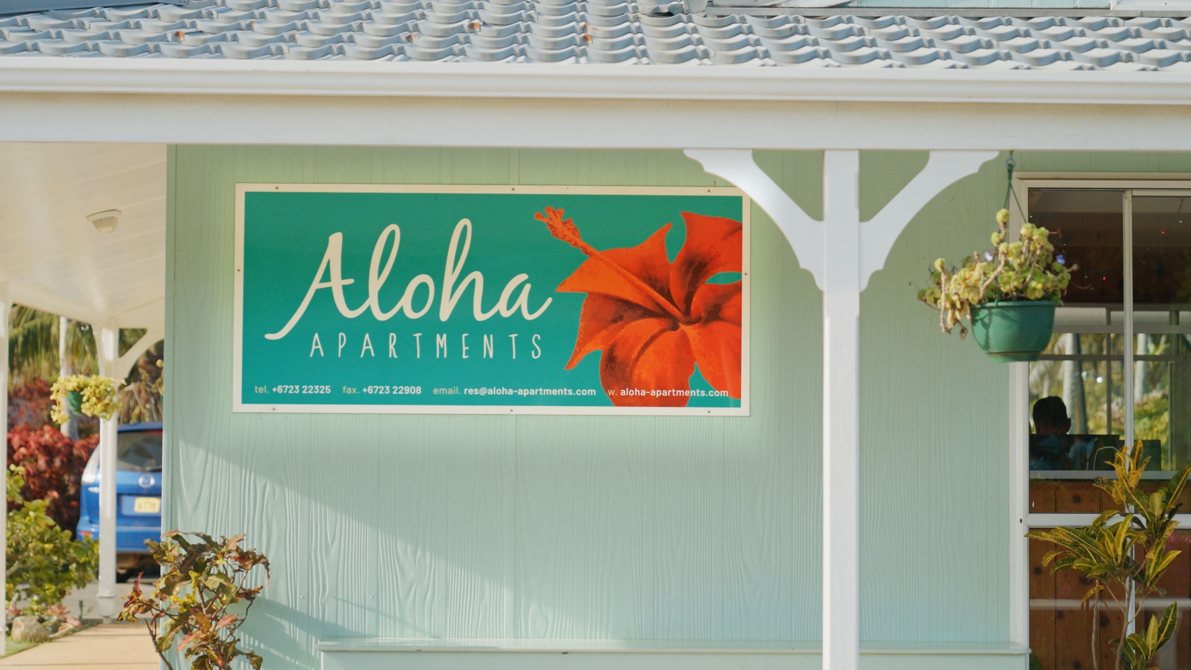 A building with a sign advertising Aloha Apartments, including contact information.