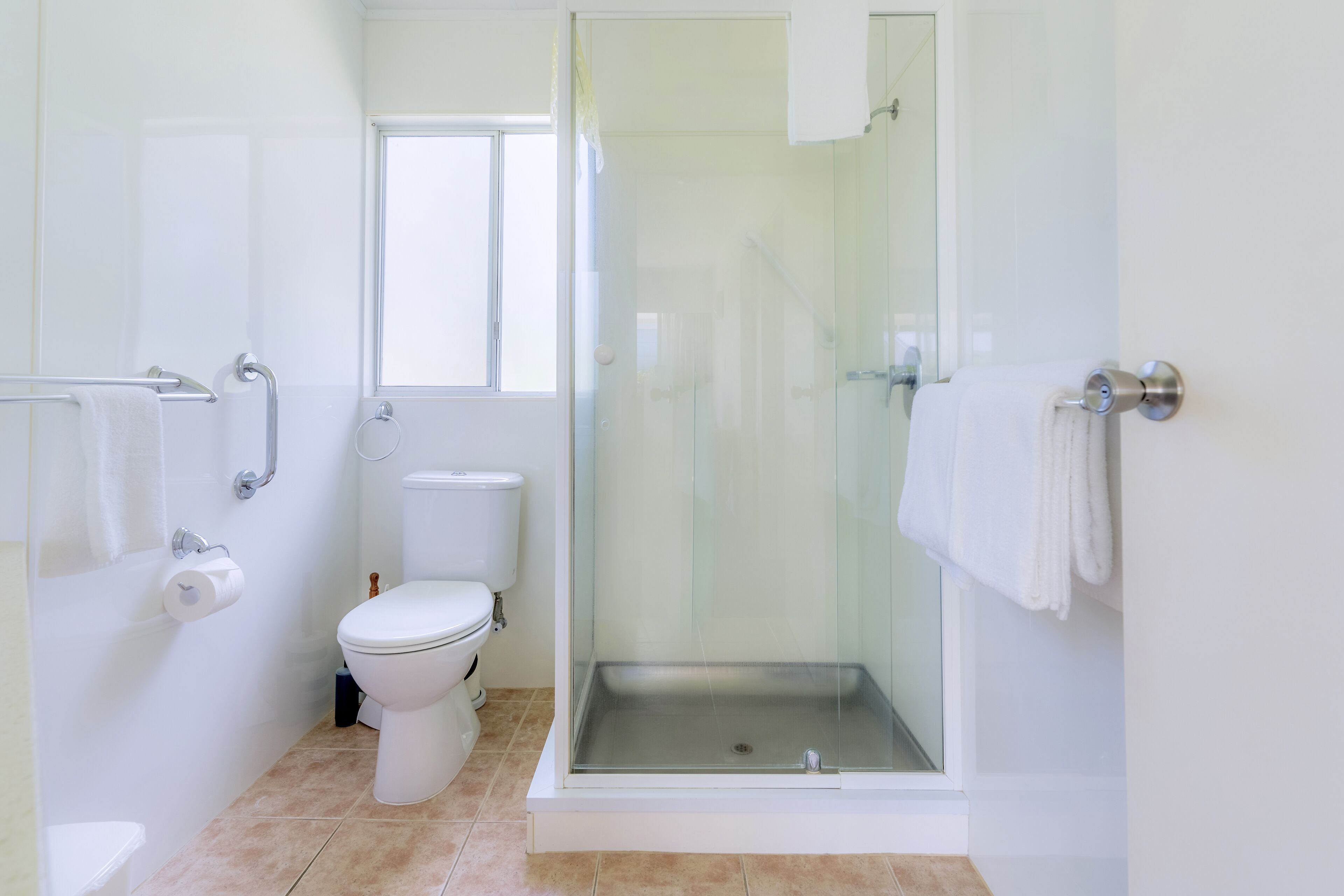 Un baño moderno con inodoro, ducha envuelta en vidrio y lavamanos blanco.