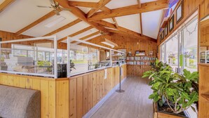 A wooden interior with a counter, bookshelves, and a large potted plant. - Aloha Apartments (Norfolk Island)