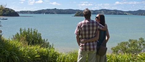 A couple standing by a lake with a view of distant hills.