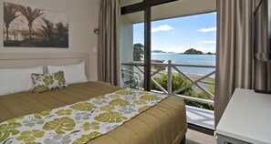 Habitación de hotel con cama, un cuadro en la pared y un balcón con vista al mar.