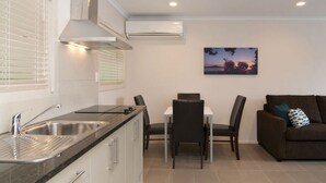 A compact living space with a kitchenette, dining area, and a sofa. - Breakwater Motel (Paihia)