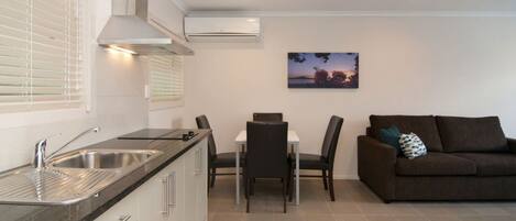 Un espacio habitable compacto con kitchenette, comedor y sofá.