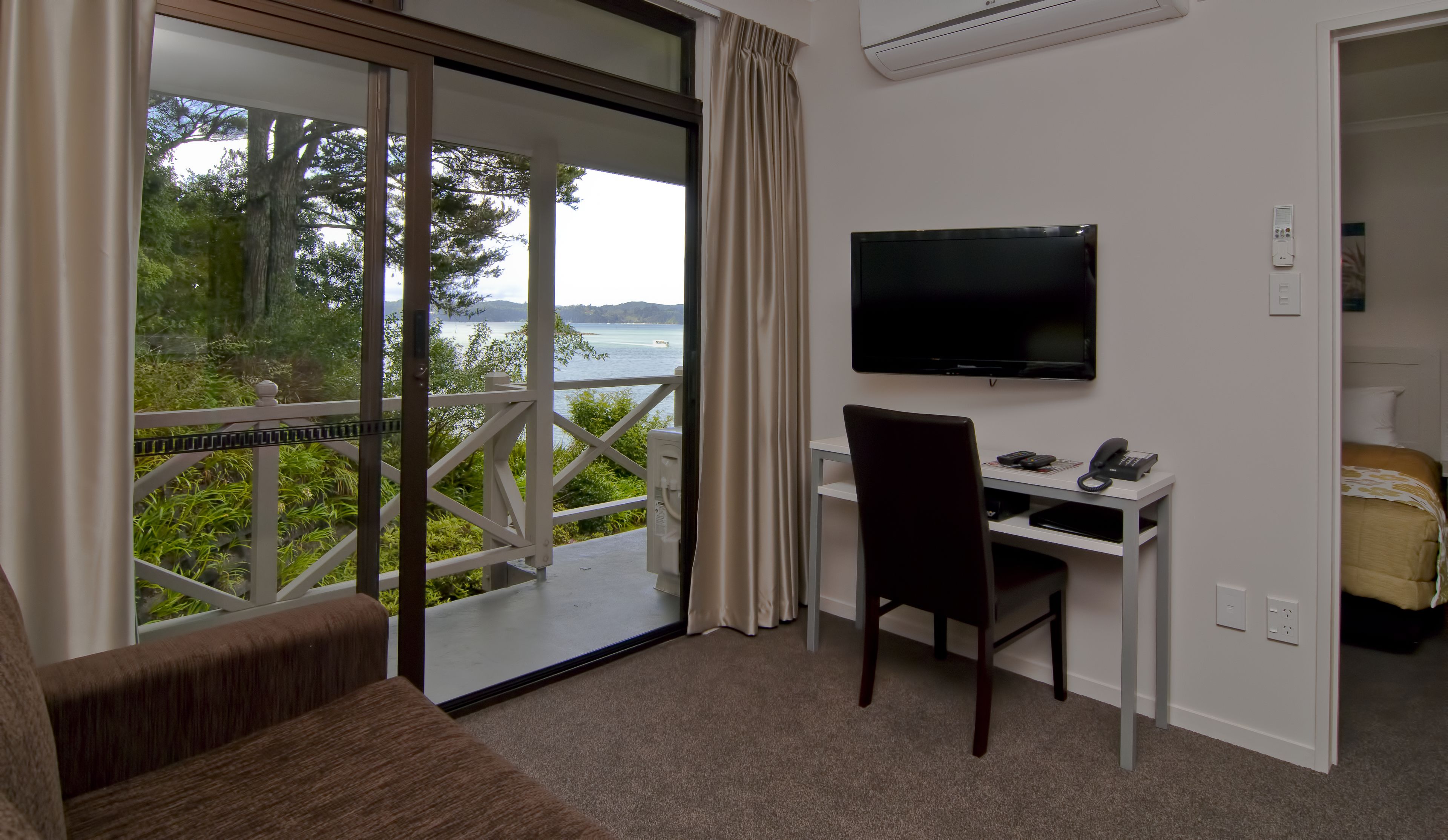 A room with a desk, chair, TV, and a bed.