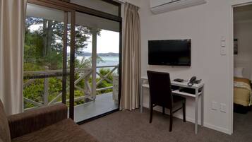 A room with a desk, chair, TV, and a bed.