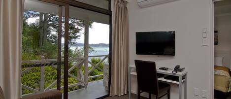 A room with a desk, chair, TV, and a bed.
