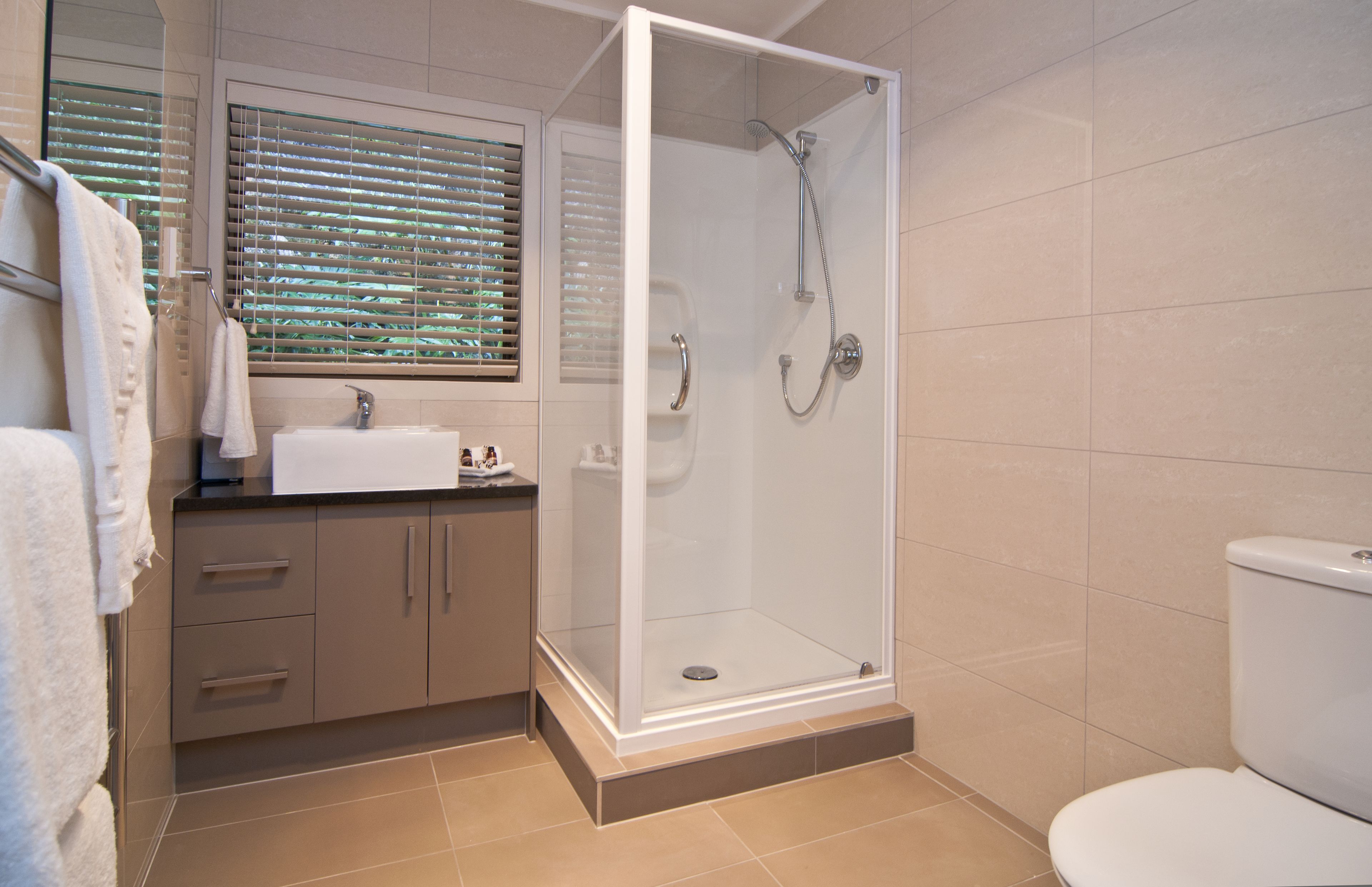 A modern bathroom with a glass-enclosed shower, a sink, and a toilet.