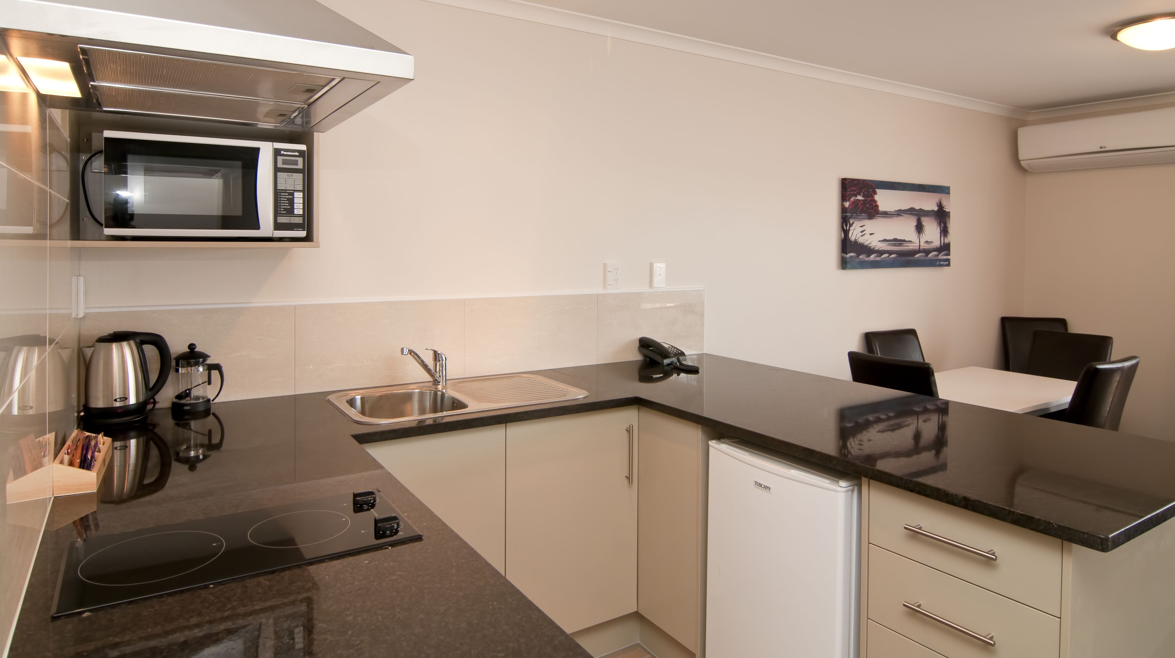 A modern kitchen with a microwave, coffee maker, sink, and a refrigerator.