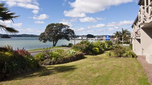 A view of a lakeside area with a motel sign, a large tree, and a building with a balcony. - Breakwater Motel (Paihia)