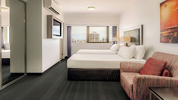A hotel room with two beds, a sofa, a TV, and a painting. - Courtyard By Marriott Darwin (Darwin)