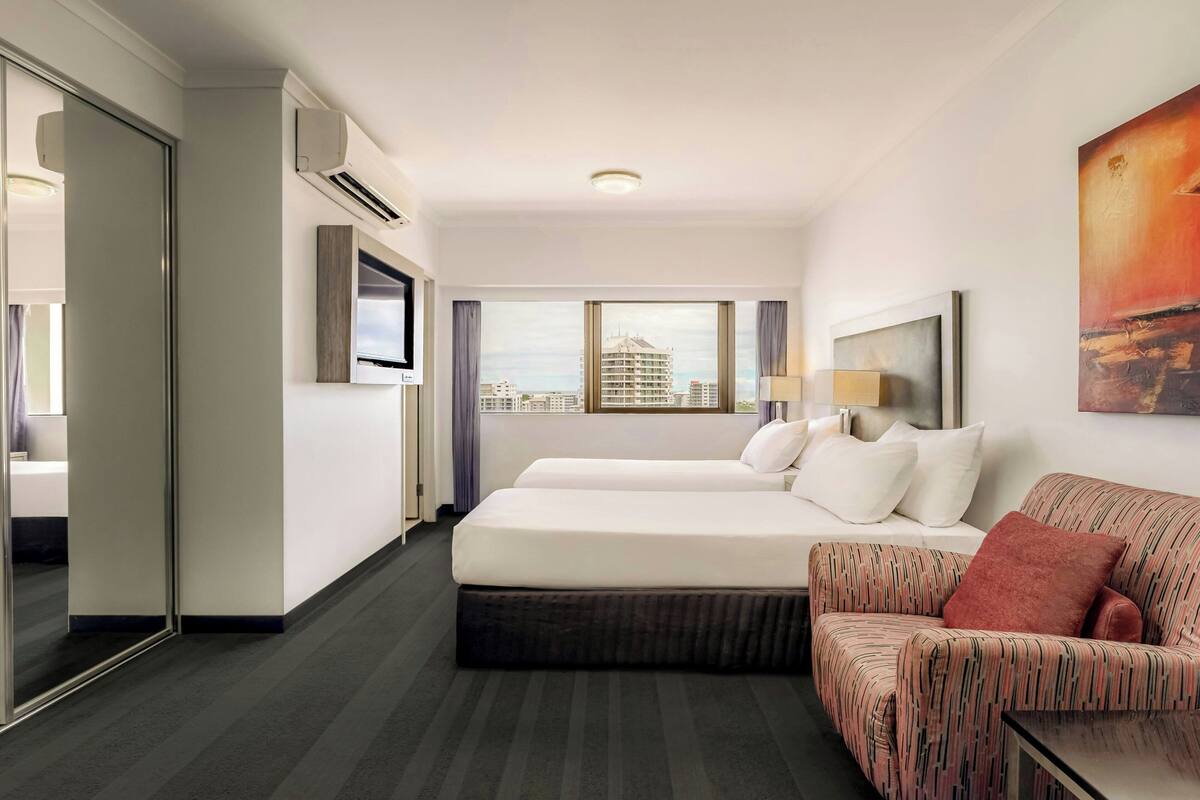 Habitación de hotel con dos camas, un sofá, un televisor y un cuadro.