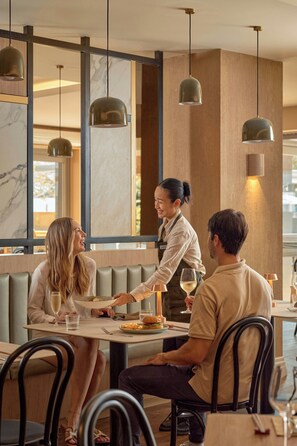 A restaurant interior with a modern design, featuring marble walls, pendant lighting, and a casual dining setup. - Courtyard By Marriott Darwin (Darwin)