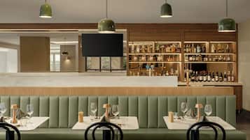 A bar area with a long counter, multiple shelves of bottles, and a seating area with tables and chairs.