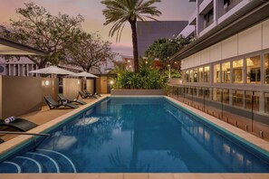 Una piscina al aire libre, sillones reclinables de piscina