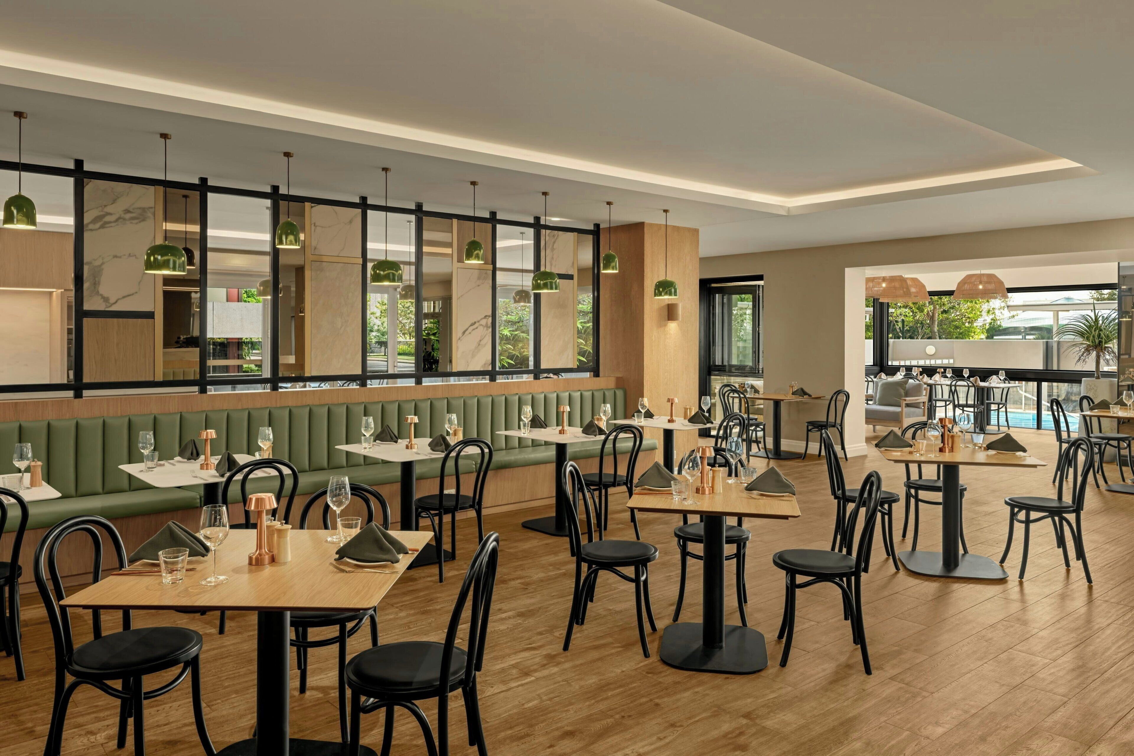 A restaurant interior with booths, tables, and hanging pendant lights.