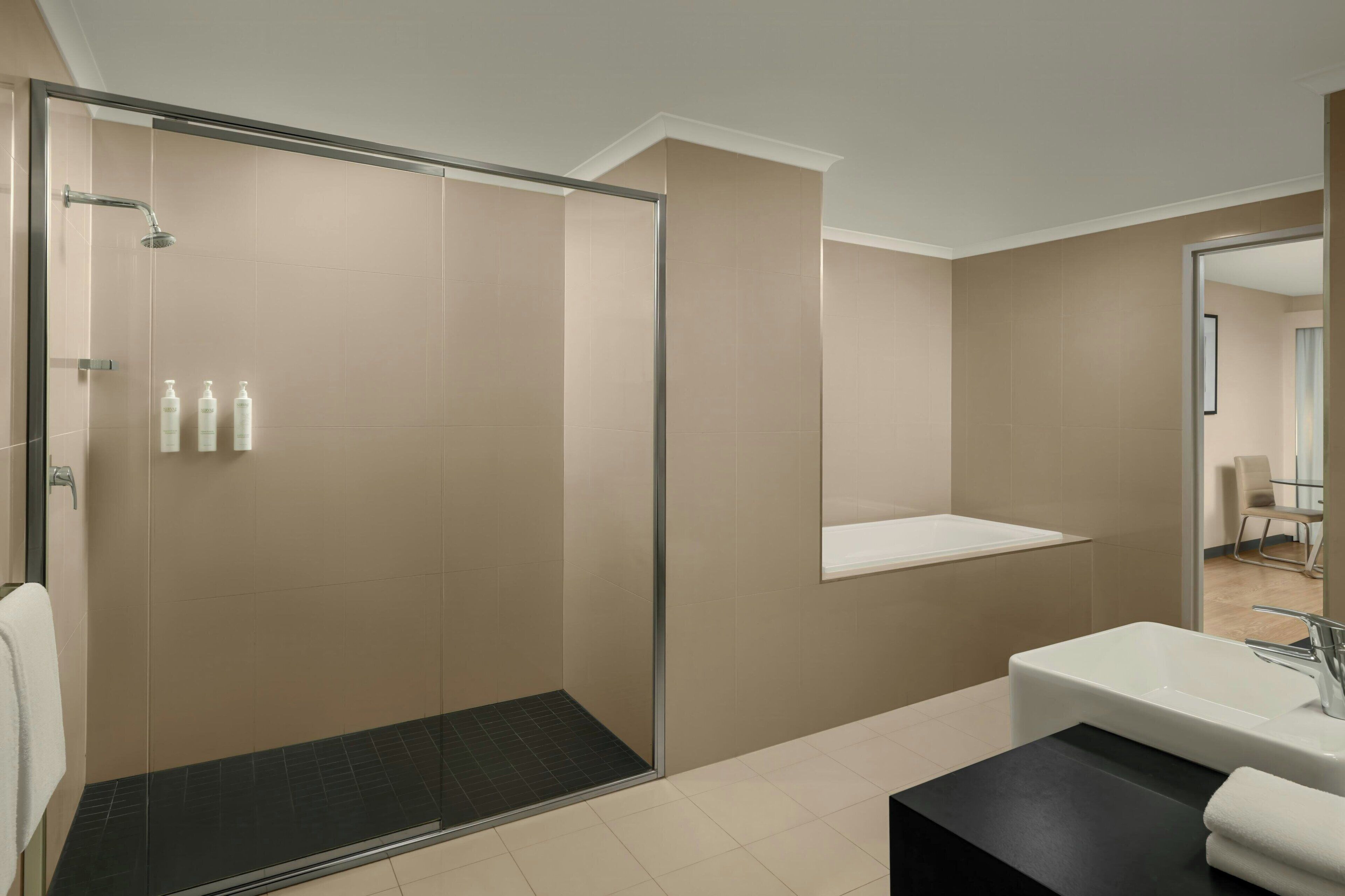 A modern bathroom with a glass-enclosed shower, a bathtub, and a vanity with a mirror.