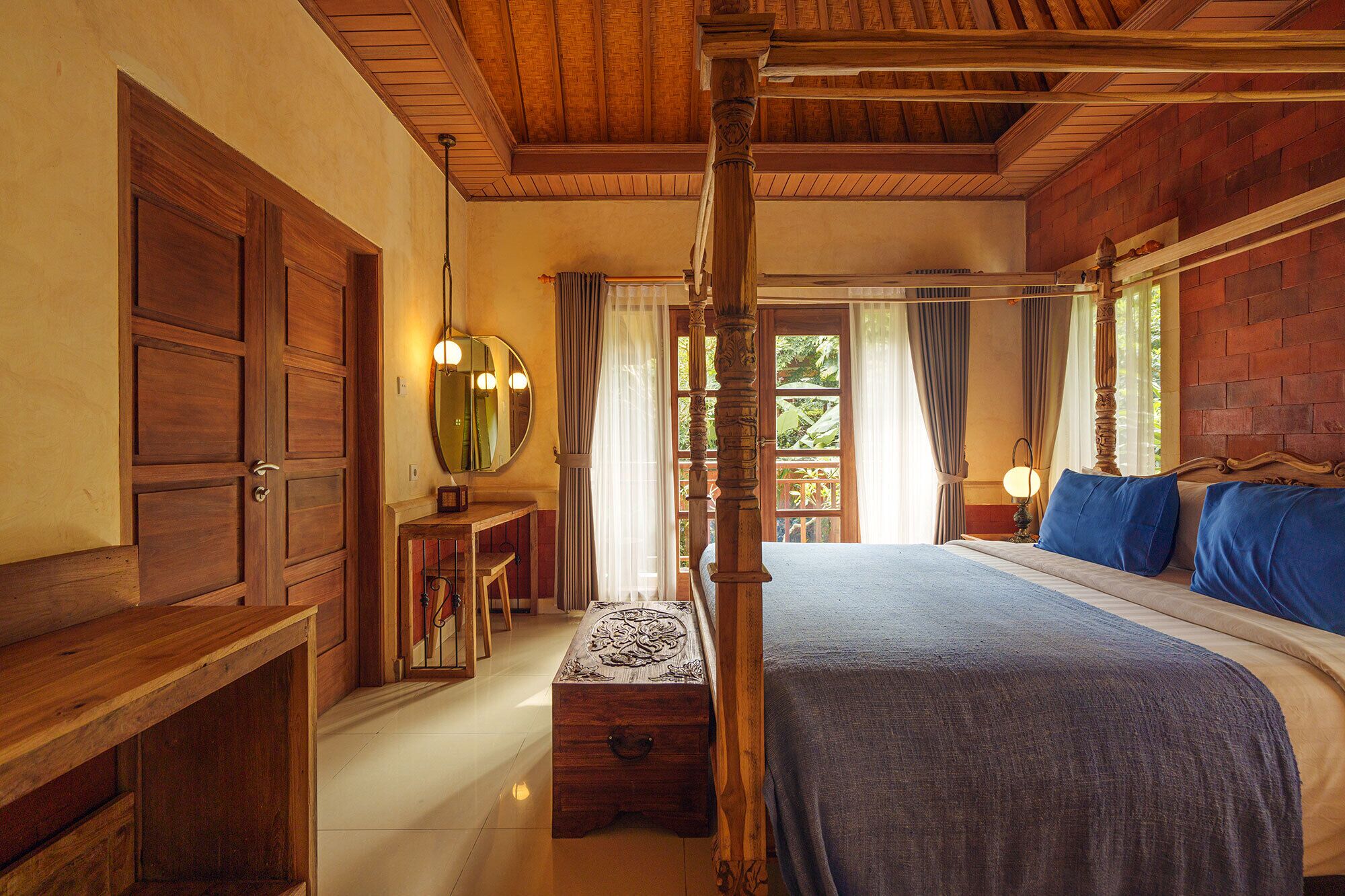 Habitación tradicional con cama con dosel, muebles de madera y vistas a través de una ventana con cortinas.