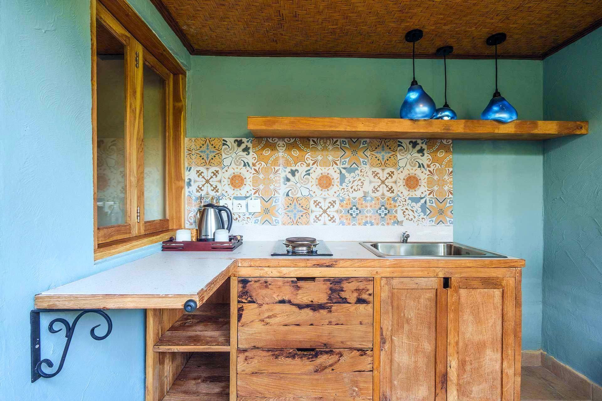 A kitchen with a wooden countertop, a sink, a stove, and a backsplash with patterned tiles.
