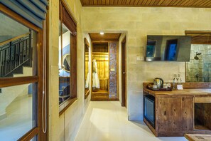 Un pasillo que conduce a una zona de cocina de madera con horno empotrado y un espejo grande sobre la encimera.