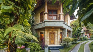 A two-story building with a stone facade, a balcony with wooden railings, and a large ornate door. - Rama Phala Resort & Spa (Ubud)