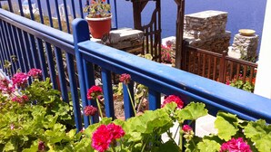 A balcony with blue railings, potted plants, and a view of the sea. - Bilios Apartments (Fournoi)