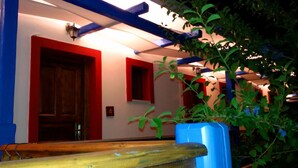 A hallway with a wooden door, a small window, and a blue wall. - Bilios Apartments (Fournoi)