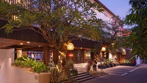 A hotel entrance with a covered outdoor area, potted plants, and a sign indicating a parking area. - The Bene Hotel (Kuta)