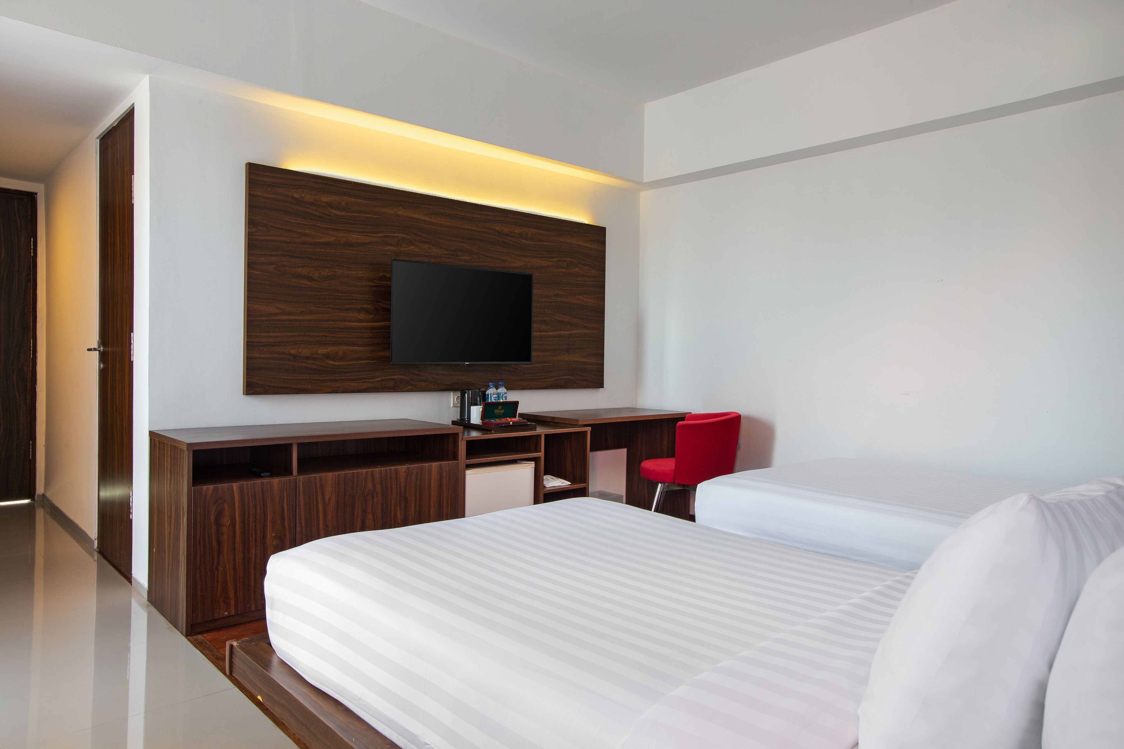 Una habitación de hotel moderna con una cama grande, un escritorio con televisión de pantalla plana y una silla roja.