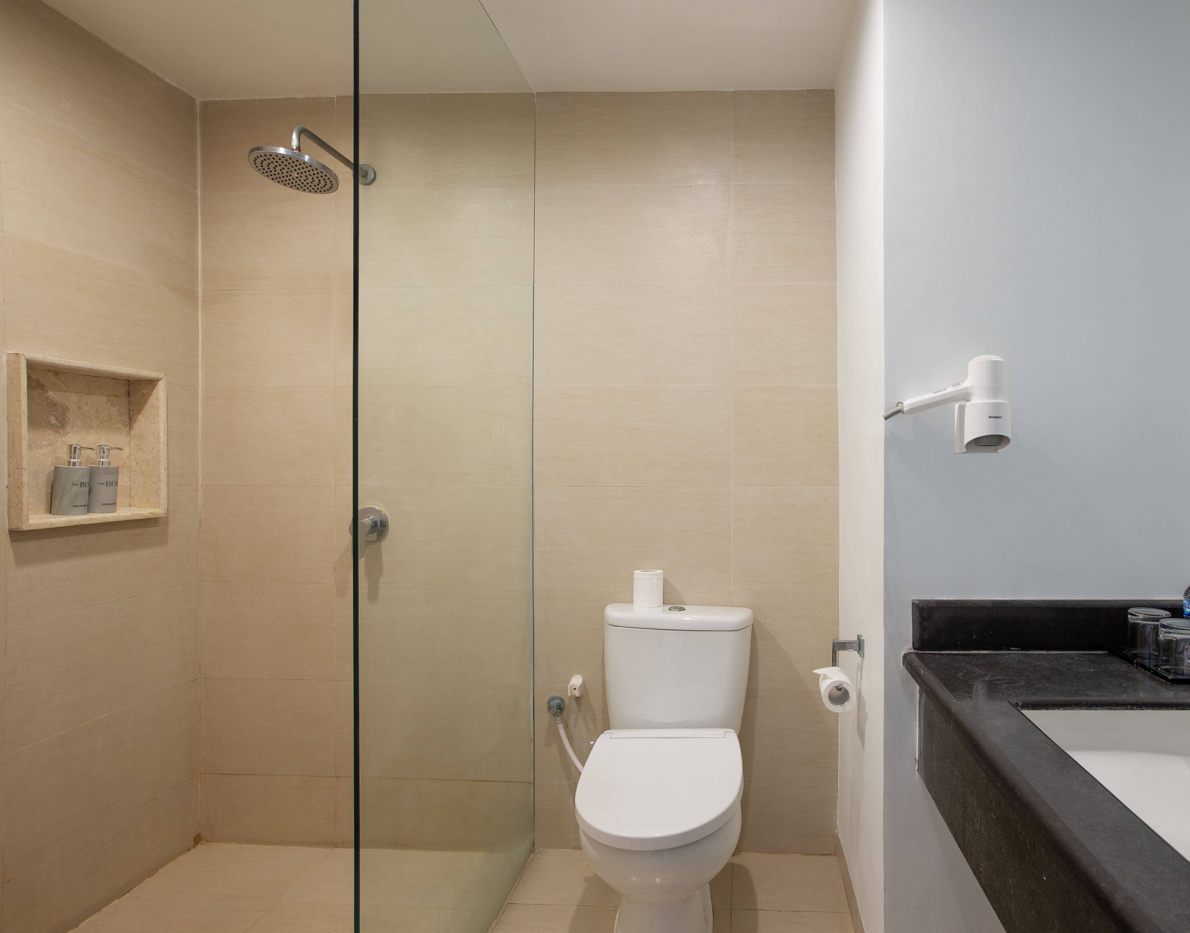 A modern bathroom with a glass-enclosed shower, a toilet, and a sink with a black countertop.