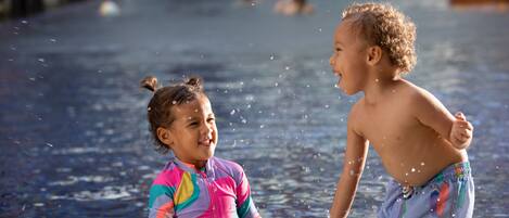 Zwei Kinder planschen im Pool, Wasser spritzt umher.