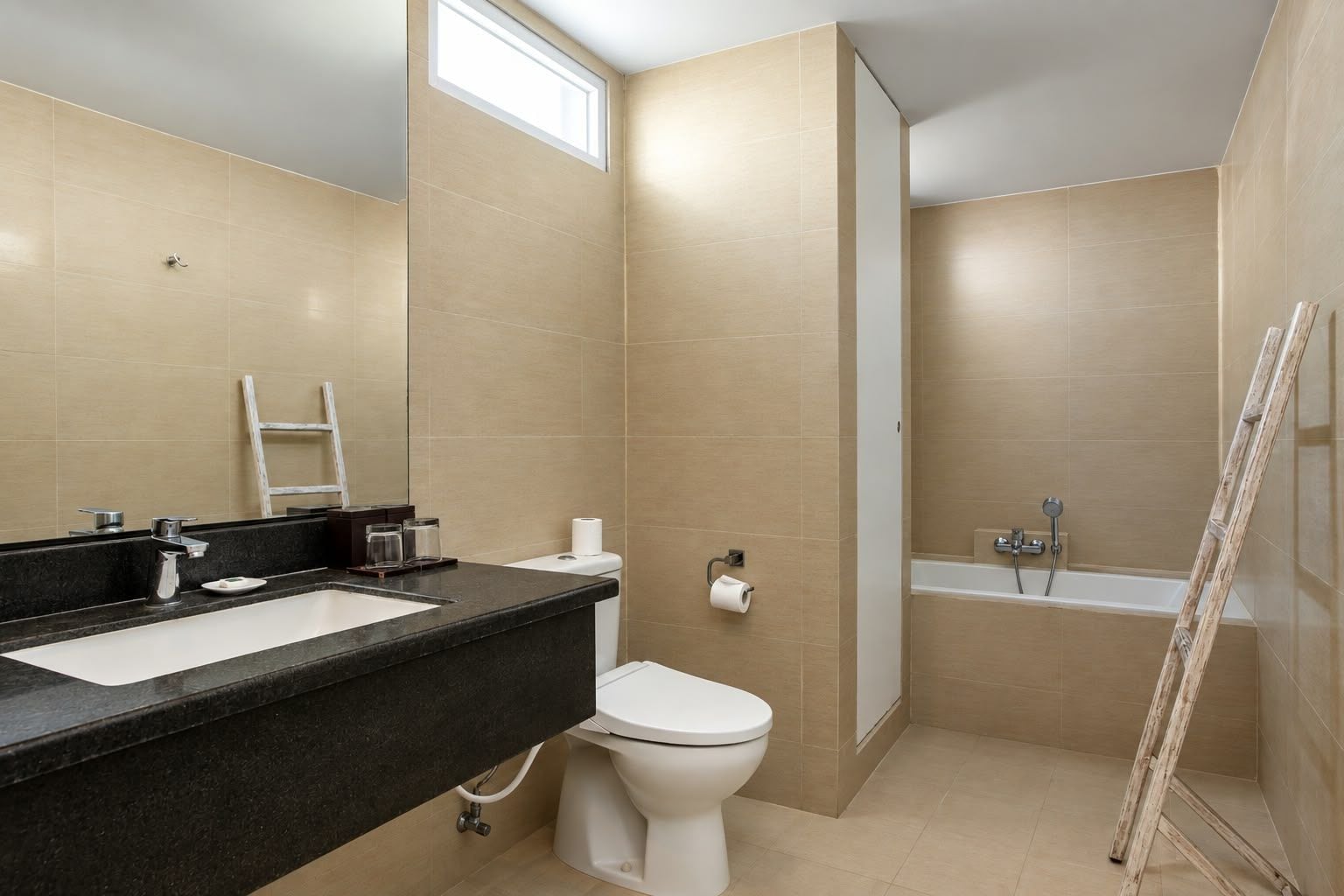 A bathroom with a black countertop, a white toilet, and a shower area.