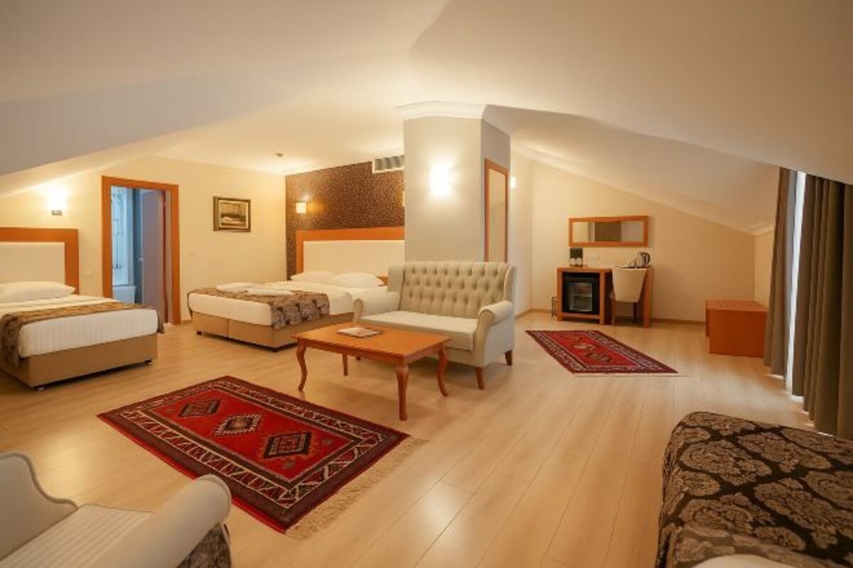 A hotel room with a bed, sofa, armchair, desk, and a small table.