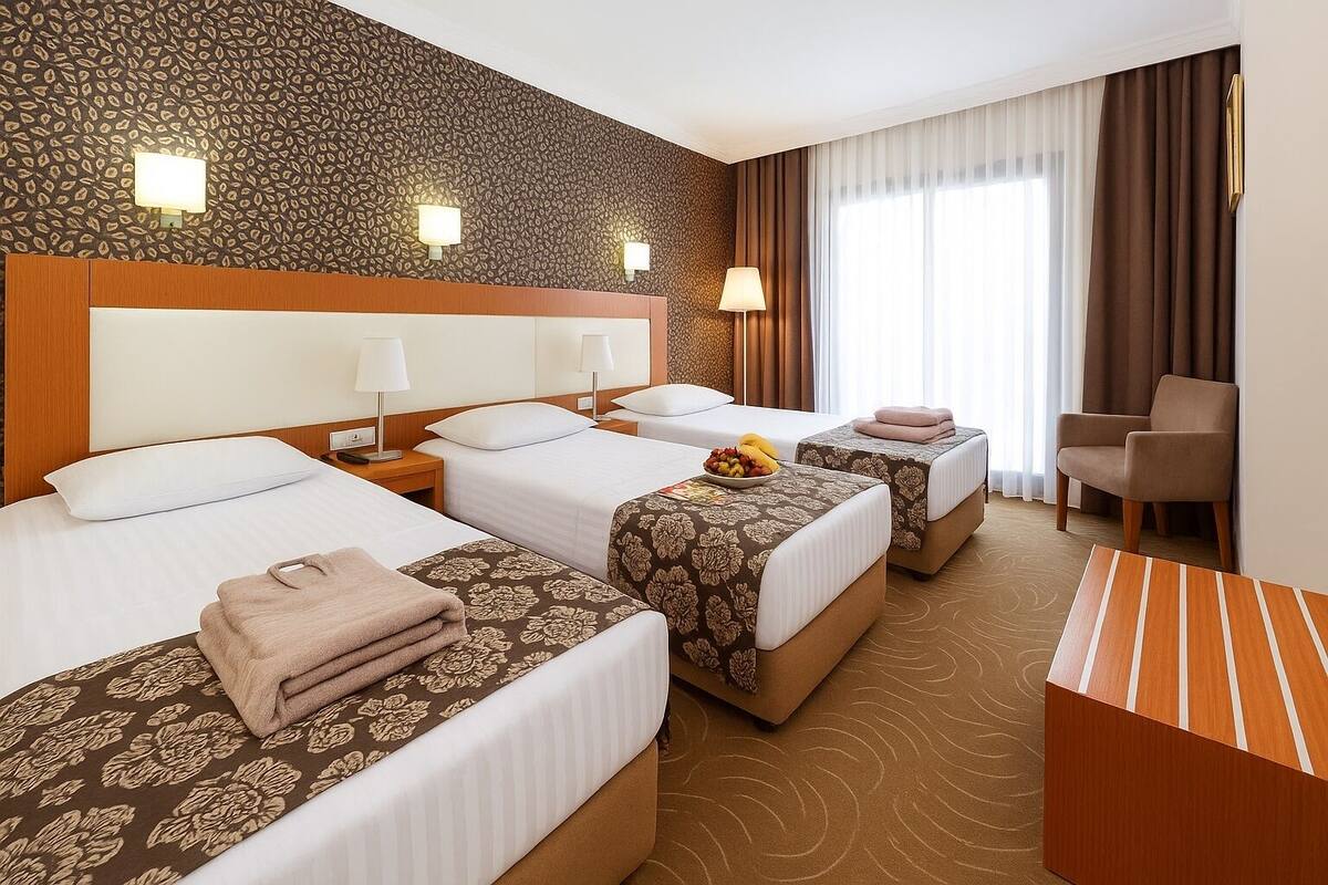 A hotel room with three beds, a desk, and a chair.