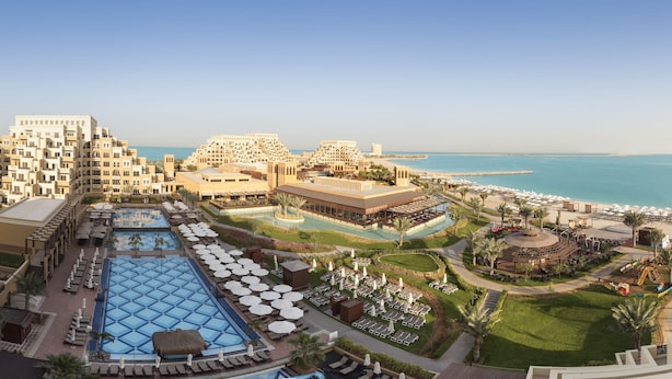 Un resort con diverse piscine, lettini e una spiaggia.