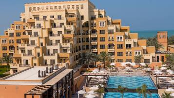 Un hotel con varios balcones, piscina y vistas al mar.