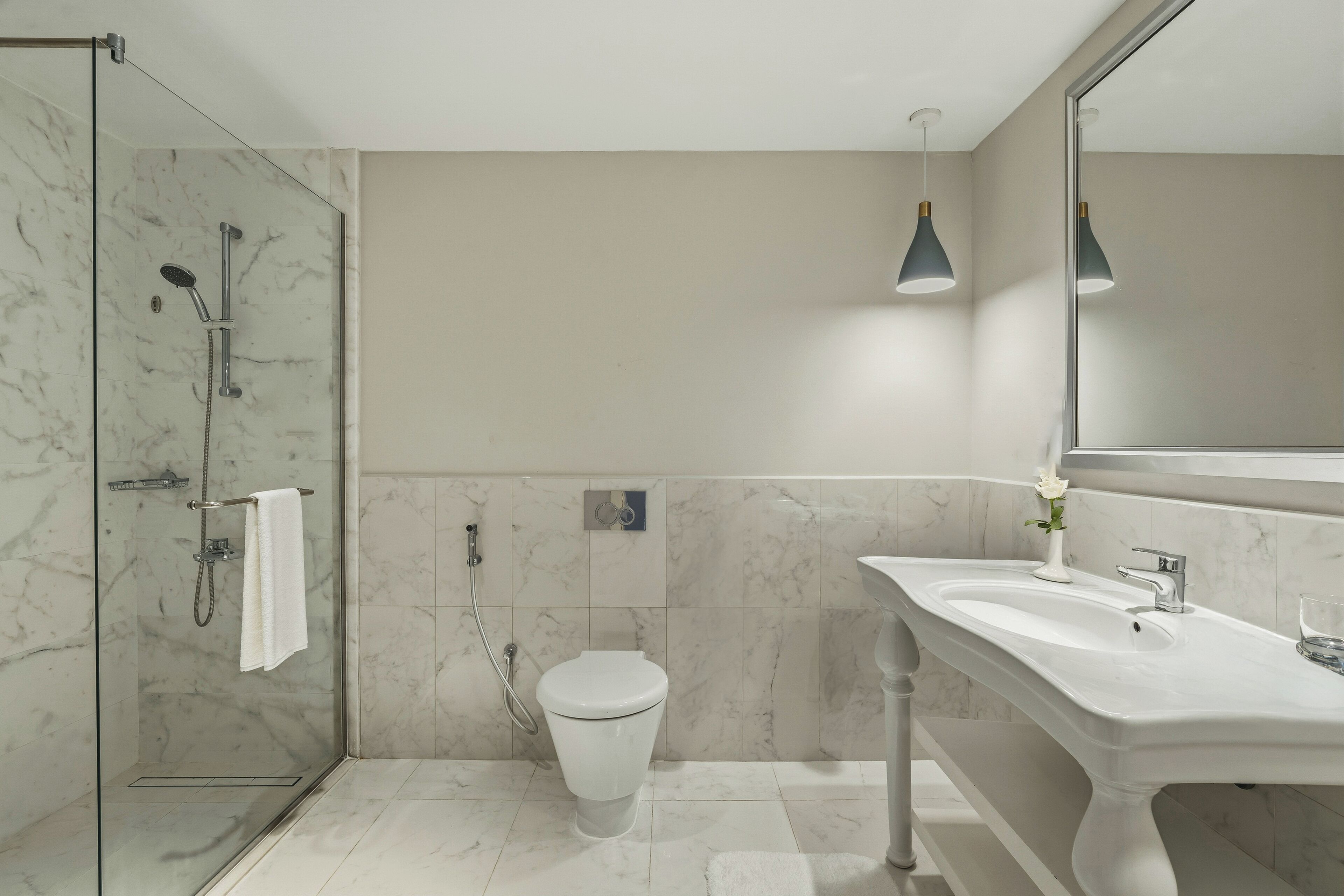 Un bagno moderno con cabina doccia in vetro, un water bianco e un lavandino grande con specchio.