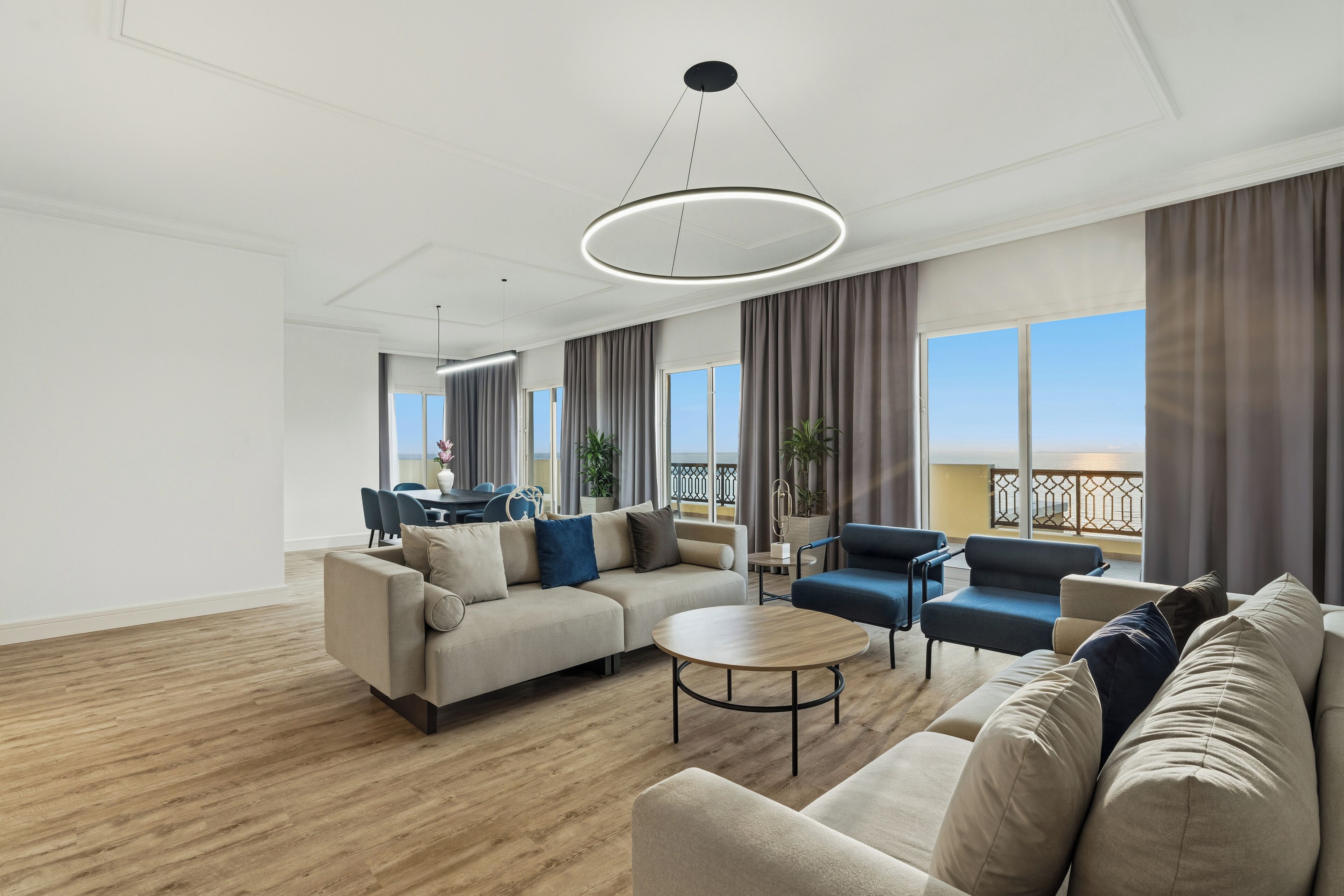 A spacious living room with a sofa, armchairs, a coffee table, and a dining area with chairs.