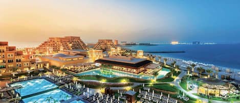 A resort with multiple swimming pools, a beach, and a view of the sea.