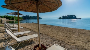 A beach with sun umbrellas and lounge chairs. - Aegli Hotel (Corfu)