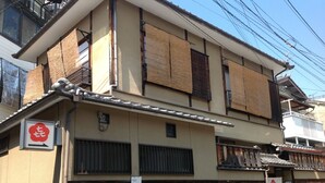 A traditional Japanese building with multiple floors, wooden shoji screens, and a sign indicating a restaurant. - Hanakiya (Kyoto)