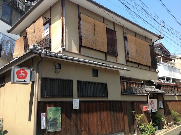 Un edificio japonés tradicional de varios pisos, con puertas correderas de madera tipo shoji y un letrero que indica un restaurante.