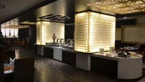 A modern hotel lobby with a central reception desk, patterned light fixtures, and a marble floor. - Rivatas (Varanasi)