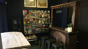 A bar area with a wooden counter, stools, and a wall decorated with travel books. - Hello Adelaide Motel and Apartments (Frewville)