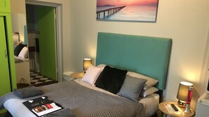 A neatly made bed with pillows and a blanket, a bedside table with a lamp, and a painting of a pier on the wall. - Hello Adelaide Motel and Apartments (Frewville)
