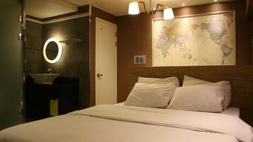 Quarto de hotel com cama, banheiro com pia e espelho, e um mapa-múndi na parede.