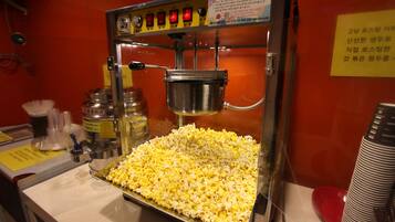 En popcornmaskin med en bricka full med popcorn och en metallbehållare ovanför.