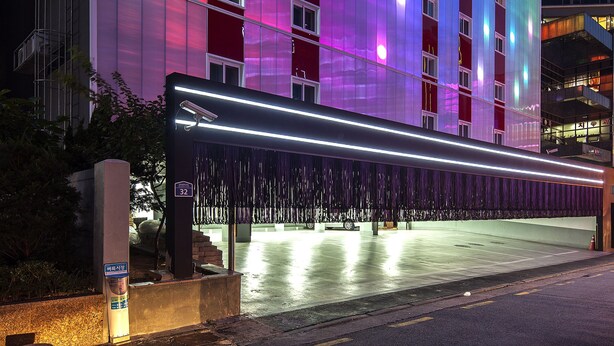 Un hotel con facciata moderna, caratterizzata da ampie finestre verticali e rivestimento colorato.