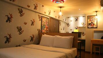 A bedroom with a bed, a desk, and a wall with superhero-themed decals.