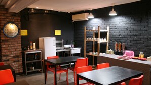 Un'area pranzo moderna con una parete in mattoni neri, un frigorifero bianco e sedie rosse.